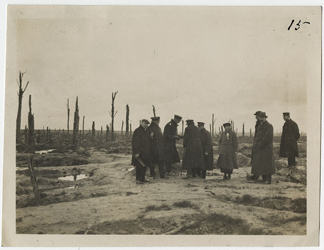 Black and white photo of a group of people meeting on a battlefield, with craters from bomb-shells filled with water 