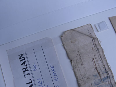 A close up of the two tags, lying flat on the mount and secured with a long strip of clear polyethylene, which has a small square magnet at one end so that it can be lifted up to release the tags.