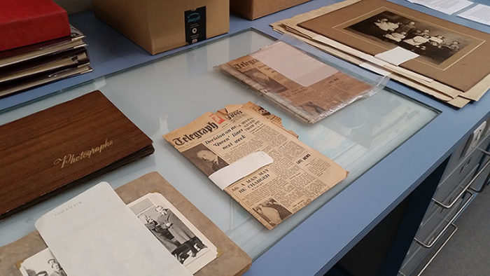 Newspapers and photograph albums laid out on a table in the Conservation Studio