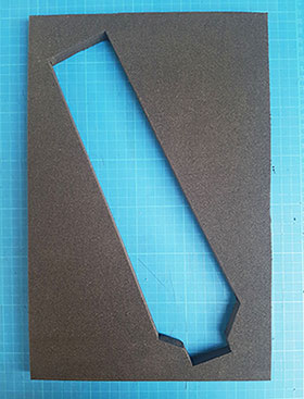A rectangular piece of grey Plastazote foam board, with a cut out in the shape of a tie folded in half