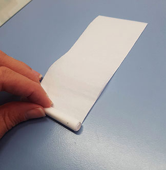A length of acid-free tissue, slightly wider than the tie, which is in the process of being rolled up.