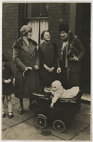 Black and white photograph of Mary Agnes Hamilton with two other women, a child, and a baby in a pram, on the street in Blackburn