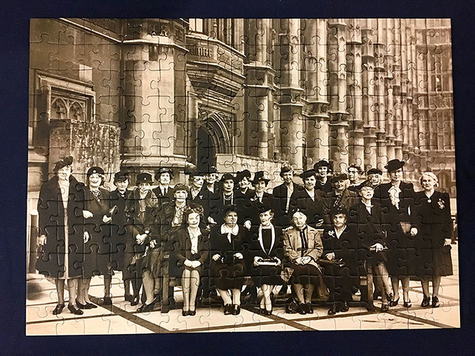 A completed jigsaw puzzle. The image is a black and white photograph of female parliamentarians outside Westminster