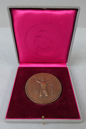 A medal in a presentation box. This has a longer inscription and the image of a man's body 