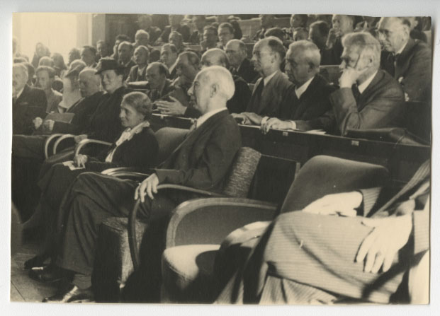 Black and white photograph of a full lecture theatre. Lise Meitner is seated on the front row.