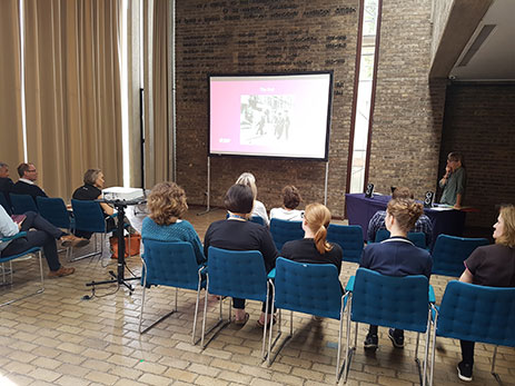 Conservator Sarah Lewery giving a powerpoint presentation to a group of staff in the Jock Colville Hall