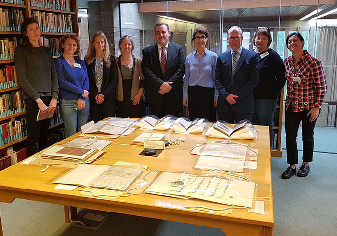 A group of people standing in the Archives Centre reading room, where there is an exhibition of papers by Elisabeth Amery