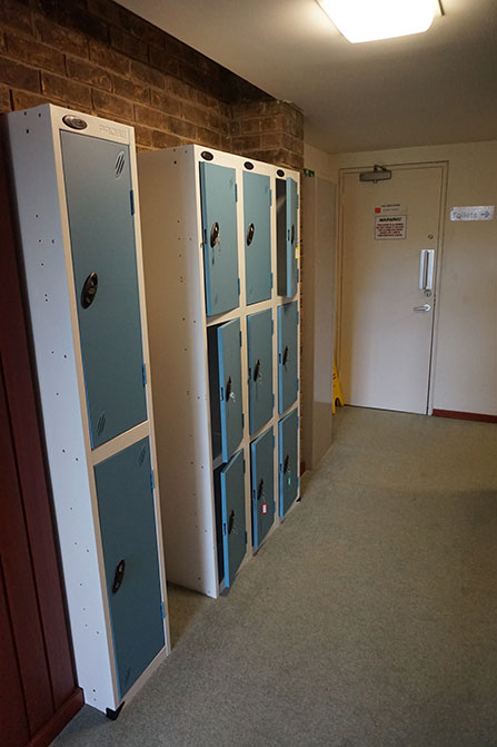 The landing outside the reading room before the refurbishment. A bank of lockers faces the lift entrance. There is a closed door at the far end of the corridor.
