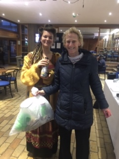 Edie Turner and Professor Dame Athene Donald standing in the Buttery holding a bag of rubbish and an ecobrick (a plastic bottle stuffed full of collected plastic waste).