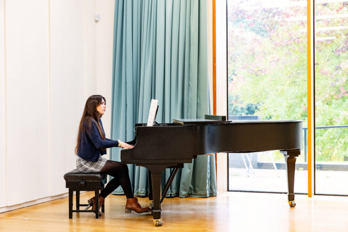A female student playing the grand piano in the Music Centre
