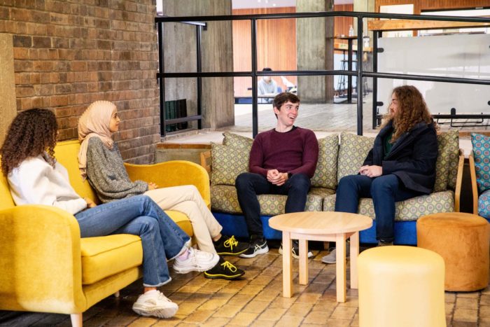 A group of four students sitting on sofas in the Buttery