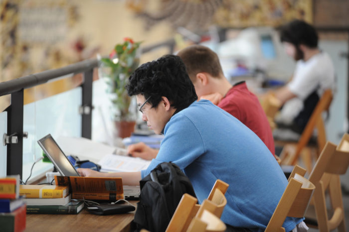Two male students working at a desk in the library