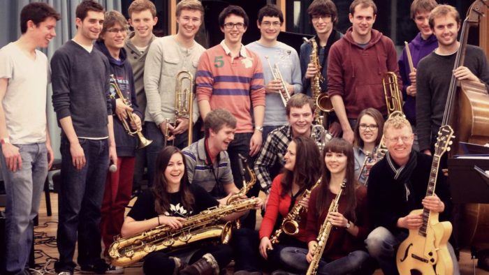 18 members of the Churchill Jazz band holding their instruments and smiling towards the camera