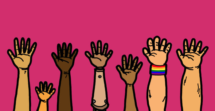 7 hands raised in front of a pink background. The hands are of varying skin tones, one is much smaller than the rest, one is an artificial arm, and one has a rainbow pride wristband