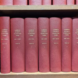 Volumes of examination papers bound in red leather on library bookshelves