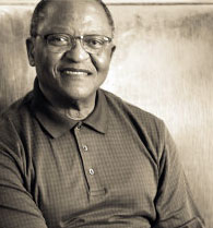 Black and white profile photo of Njabulo Ndebele. He is smiling at the camera