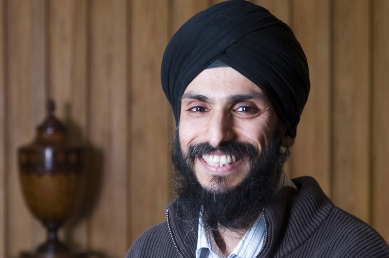 Profile photo of Sumeetpal Singh. He is standing in a wood panelled room and smiling at the camera.