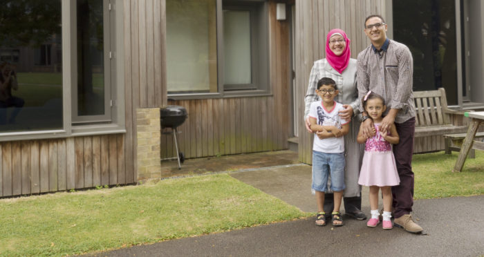 A couple and their two children standing outside postgraduate accommodation