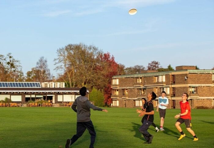 Four students play ultimate frisbee outside on a sunny day