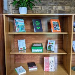 Bookshelves in the Bracken Library foyer where books about gardening are on display next to the box containing the seed library