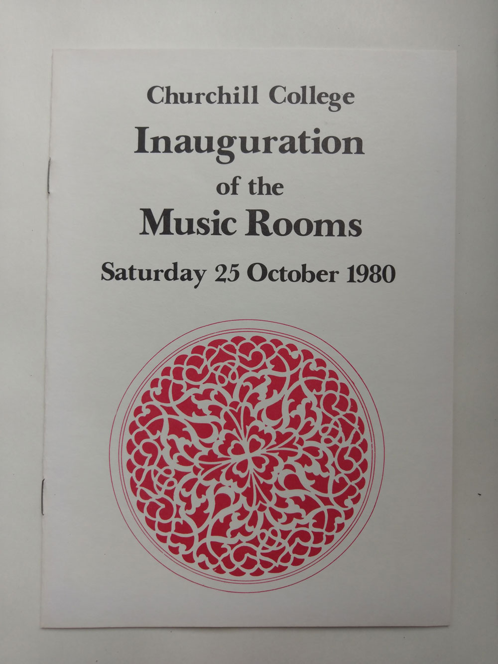 A program cover for Churchill Colleges Inauguration of the Music Rooms on Saturday, 25 October 1980. The cover features elegant serif text and a large red ornate circular design.