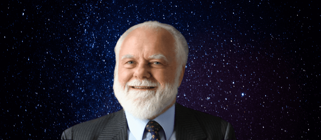 A bearded man in a suit smiles against a starry night sky background.