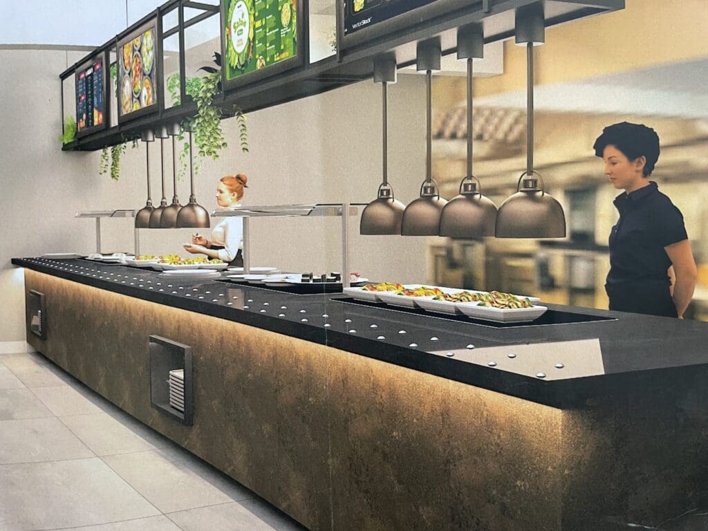 A modern buffet with sleek black surfaces and hanging lamps above. Two people are serving and arranging food under a row of menu screens. Decorative greenery hangs from the fixtures, and the floor is tiled in light gray.