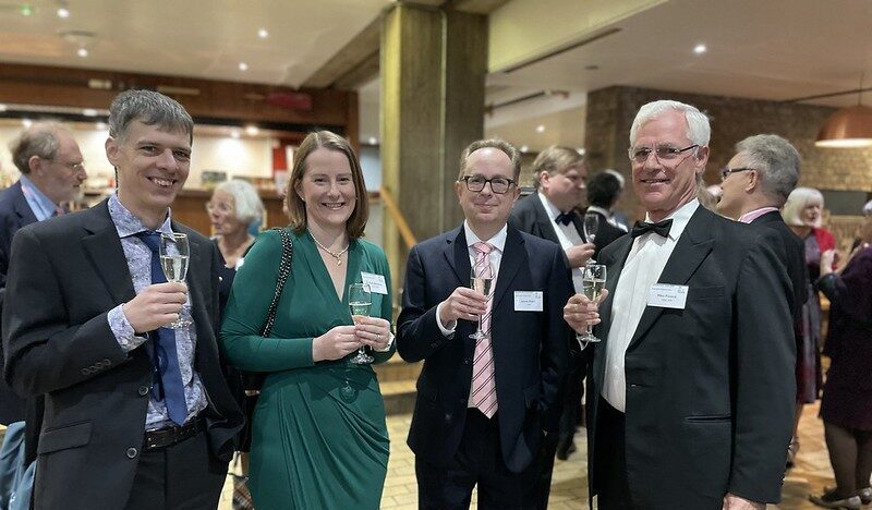 A group of five alumni holding drinks