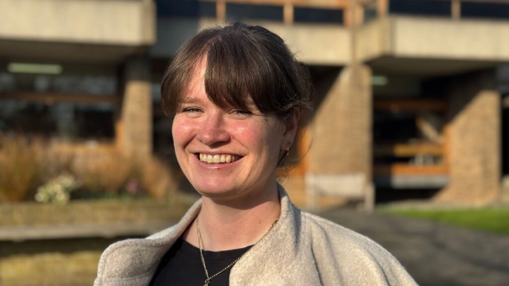 Profile image of a woman smiling at the camera standing outside a building