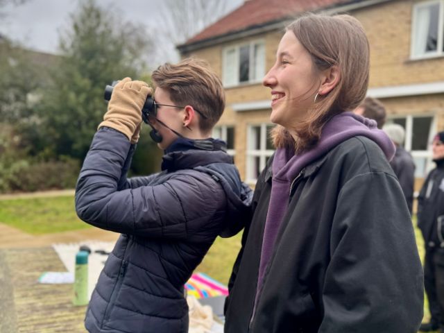 Two birdwatchers in the gardens of Churchill College