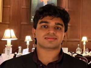 Student Aryan Sagdeo in a formal dining room with pannelling on the walls